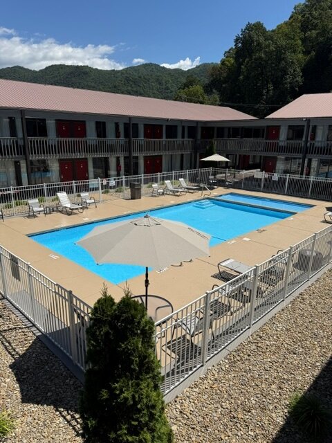 a pool with umbrella and chairs in front of a building